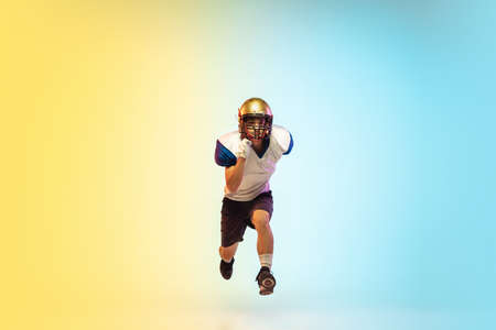 Unstoppable. American football player isolated on gradient studio background in neon light....