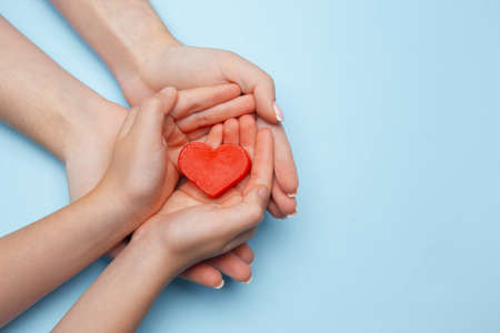 Human hands holding, giving heart isolated on blue background with copyspace. Concept of emotions, feelings, charity, family, supporting hand. Thankful, inspirational. Romantic and togetherness.の写真素材