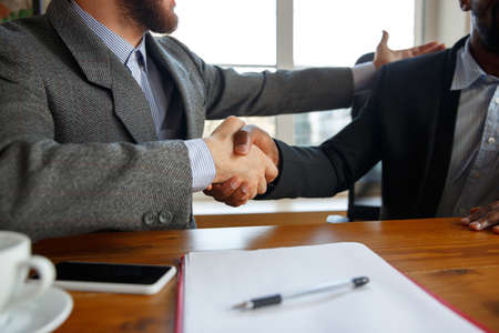 Close up of businessmen shaking hands in conference room, making a deal, successful agreement or cooperation. Concept of finance and business, contracts, partnership, community and teamwork.の写真素材