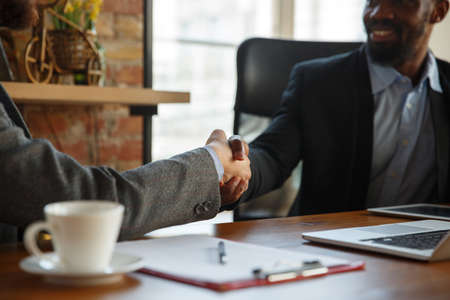 Close up of businessmen shaking hands in conference room, making a deal, successful agreement or...