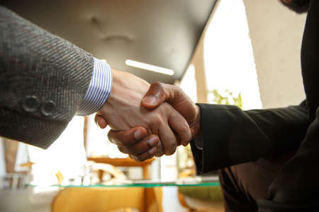 Close up of businessmen shaking hands in conference room, making a deal, successful agreement or...