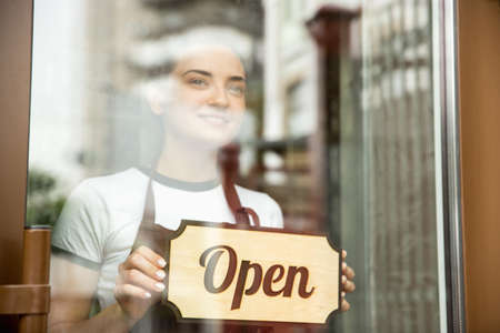 Open sign on the glass with reflection of street cafe or restaurant. Coronavirus pandemic new safety...