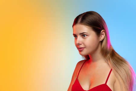 Calm. Close up caucasian young womans portrait on gradient studio background in neon. Beautiful...