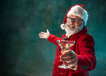 Lets party. Modern stylish Santa Claus in red fashionable suit and cowboys hat on dark background. Looks like a rockstar. New Year and Christmas eve, celebration, holidays, winters mood, fashion.の写真素材