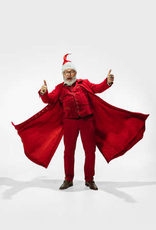 Thumb up. Modern stylish Santa Claus in red fashionable suit isolated on white background. Looks...