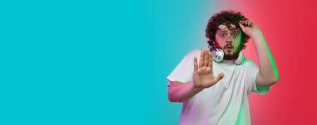 Shocked stop. Caucasian young mans portrait on gradient studio background in neon light. Beautiful...