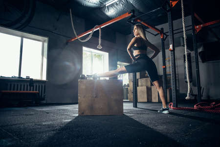 Stretching. Young caucasian female athlete training in gym, doing strength exercises, practicing....
