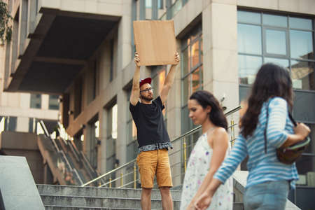 Dude with sign - man stands protesting things that annoy him. Solo demonstration his right to talk free on the street with sign. Copyspace for text. Opinion heard by public. Social life, humor, meme.の写真素材