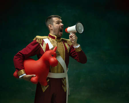 Shouting for sales. Young man in suit as Nicholas II isolated on dark green background. Retro style,...