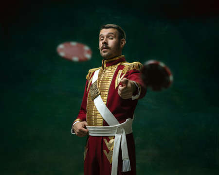 Casino winner. Young man in suit as Nicholas II isolated on dark green background. Retro style,...