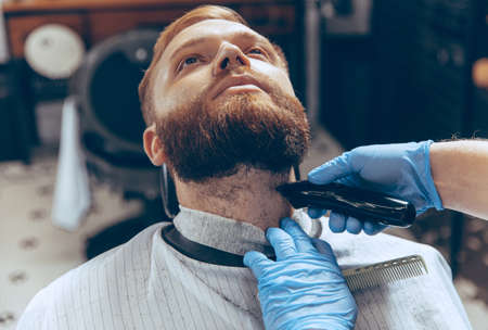Close up man getting hair cut at the barbershop wearing mask during coronavirus pandemic....