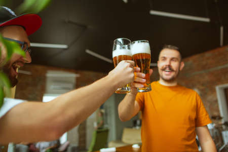 Clinking bottles. Young group of friends drinking beer, having fun, laughting and celebrating together. Women and men with beers glasses. Oktoberfest, friendship, togetherness, happiness concept.の写真素材