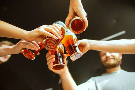 Close up clinking. Young group of friends drinking beer, having fun, laughting and celebrating together. Women and men with beers glasses. Oktoberfest, friendship, togetherness, happiness concept.の写真素材
