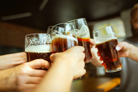 Close up clinking. Young group of friends drinking beer, having fun, laughting and celebrating together. Women and men with beers glasses. Oktoberfest, friendship, togetherness, happiness concept.の写真素材