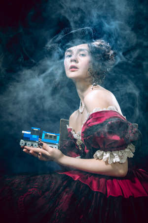 Train model. Young woman as Anna Karenina isolated on dark blue background. Retro style, comparison...