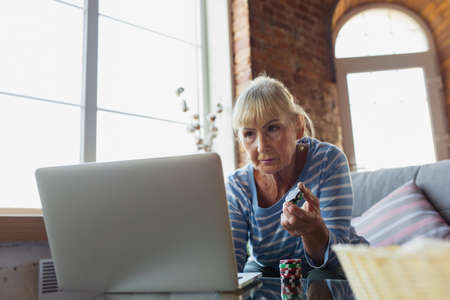 Learning to play poker. Senior woman studying at home, getting online courses, self-development....