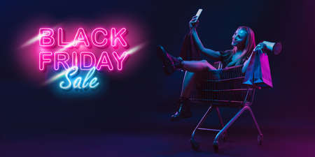 Selfie, megaphone. Portrait of young woman in neon on dark studio backgound. Human emotions, black...