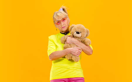 Fave toy. Senior woman in ultra trendy attire isolated on bright orange background. Looks stylish...