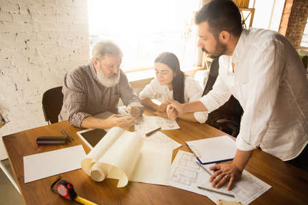 Male architect-engineer presents project of future house for young family. Man working in the office with documents, blueprint. First home, industrial, building concept. Moving to new live place.の写真素材