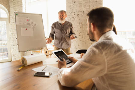 Male architect-engineer presents project of future house for young family. Man working in the office...