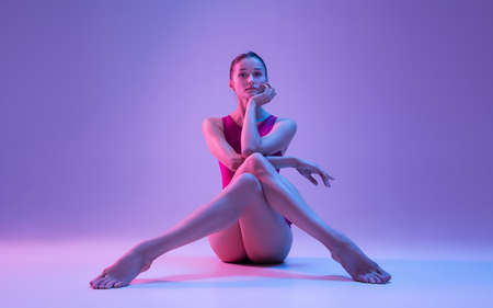 Fashion. Young and graceful ballet dancer isolated on purple studio background in neon light. Art,...