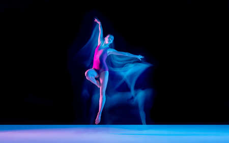 Smoke. Young and graceful ballet dancer on black studio background in neon mixed light. Art, motion,...