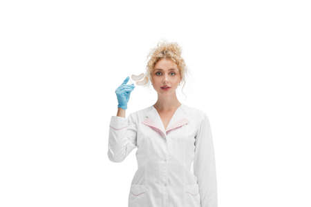 Eye patches. Portrait of female doctor, nurse or cosmetologist in white uniform and blue gloves over white studio background. Copyspace for ad. Concept of healthcare and medicine, beauty, self-care.の写真素材