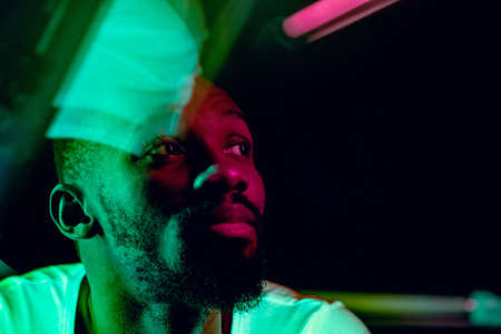 Evening mood. Cinematic portrait of stylish young man in neon lighted room. Bright neoned colors....