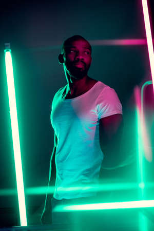Geometric lines. Cinematic portrait of stylish young man in neon lighted room. Bright neoned colors....
