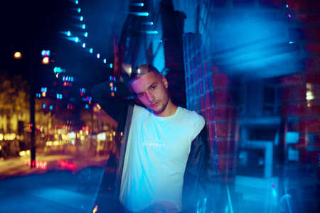Classy savaging. Cinematic portrait of stylish young man in neon lighted room. Bright neoned colors....