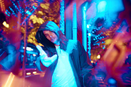 Moody and proud. Cinematic portrait of stylish young man in neon lighted room. Bright neoned colors....