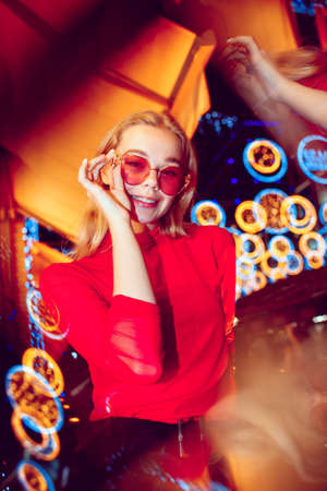 Night life. Cinematic portrait of stylish young woman in neon lighted room. Bright neoned colors. Caucasian model, musician outdoors. Youth culture in party, festival style and music concept.の写真素材