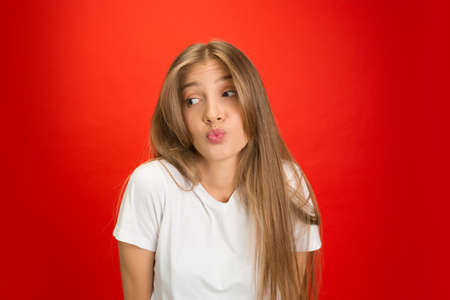 Kissing. Portrait of young caucasian woman with bright emotions on red studio background with...