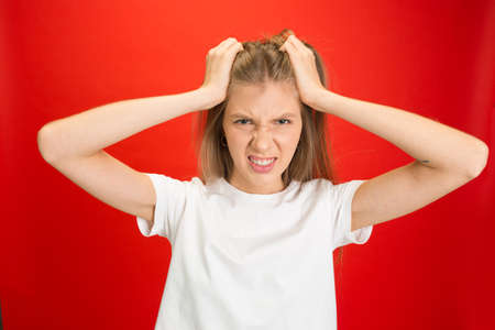 Crazy shocked, wondered. Portrait of young caucasian woman on red studio background with copyspace. Blonde female model. Concept of human emotions, facial expression, sales, advertising, youth.の写真素材