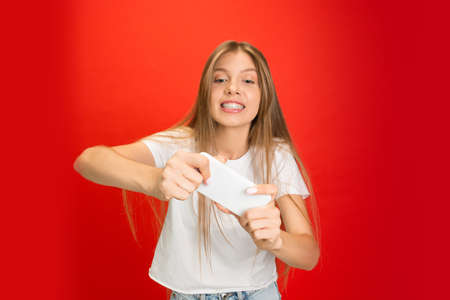 Playing games. Portrait of young caucasian woman isolated on red studio background with copyspace....