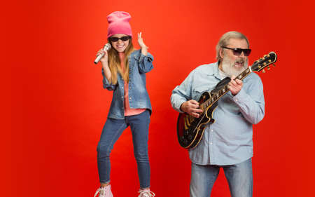 Cheerful musician. Senior man spending happy time with granddaughter in neon. Joyful elderly...
