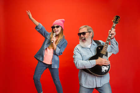 Cheerful musician. Senior man spending happy time with granddaughter in neon. Joyful elderly...