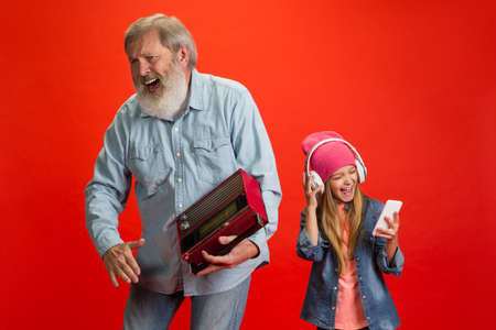 Happy mood. Senior man spending happy time with granddaughter on red background. Joyful elderly...