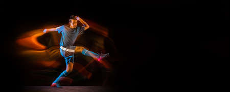Win. Football or soccer player on black studio background in mixed light. Young male sportive model...