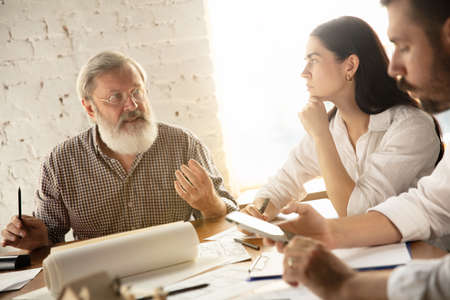 Male architect-engineer presents project of future house for young family. Man working in the office with documents, blueprint. First home, industrial, building concept. Moving to new live place.の写真素材