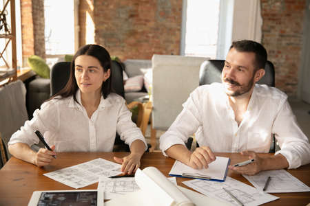 Young family listening to male architect-engineer presents project . Working in the office with...
