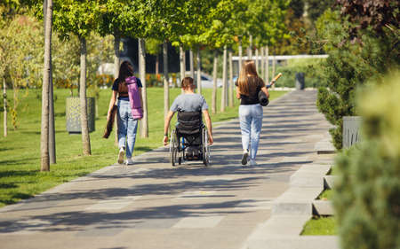 Summer. Happy caucasian handicapped man on a wheelchair spending time with friends playing live...
