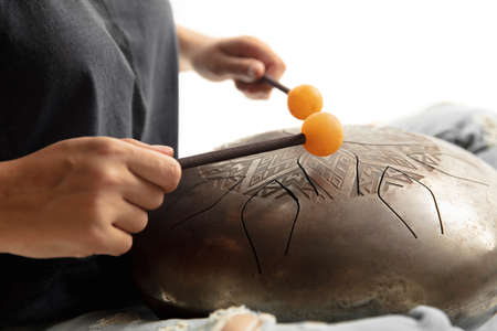 A close up of hands playing the hank drum on white studio background. Concept of hobby, professional...
