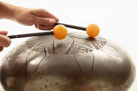 A close up of hands playing the hank drum on white studio background. Concept of hobby, professional...