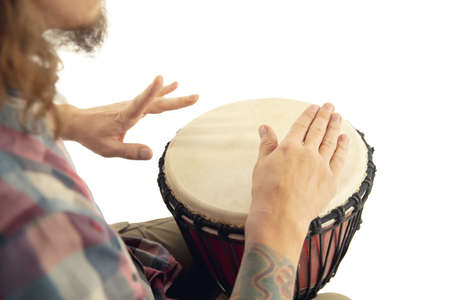 Man plays ethnic drum darbuka percussion, close up musician isolated on white studio background. Male hands tapping djembe, bongo in rhythm. Musical handmade instruments, world culture sound.の写真素材