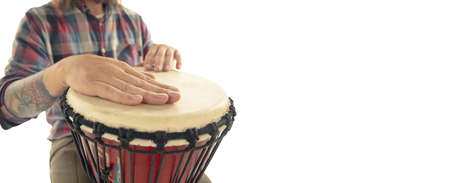 Man plays ethnic drum darbuka percussion, close up musician isolated on white studio background. Male hands tapping djembe, bongo in rhythm. Musical handmade instruments, world culture sound.の写真素材