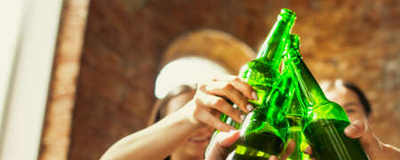 Cheers. Hands of friends, colleagues during beer drinking, having fun, clinking bottles, glasses together. Flyer with copyspace. Oktoberfest, friendship, togetherness, happiness holidays conceptの写真素材
