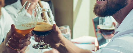Good vibes. Hands of friends, colleagues during beer drinking, having fun, clinking bottles, glasses...