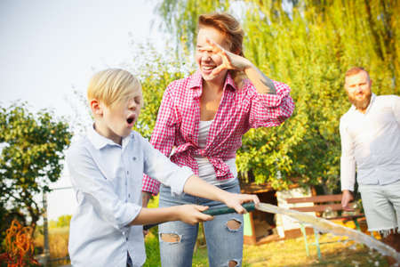 Comfortable feels. Happy family during watering plants in a garden outdoors. Love, family,...