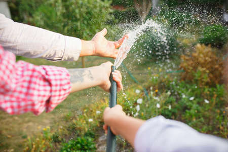Domestic life. Happy family during watering plants in a garden outdoors. Love, family, lifestyle,...